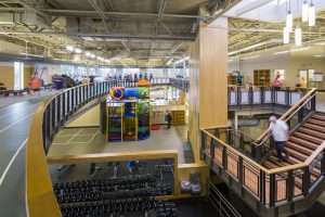 Gordon Family YMCA interior from second level showing running lane, exercise equipment, and children's play equipment, Sumner, WA
