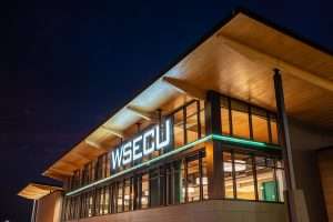 WSECU Building exterior at night, showing wood roof overhang illuminated by light.