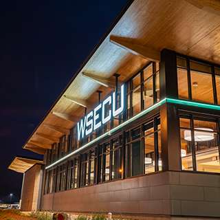 WSECU Building exterior at night, showing wood roof overhang illuminated by light.