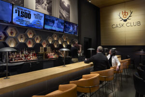 Two people sit and enjoy drinks at a warmly lit bar.