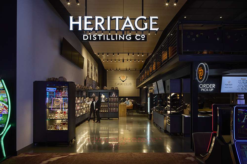 The entry to a dimly lit tasting room space. A sign over the entry reads, "Heritage Distilling Co."