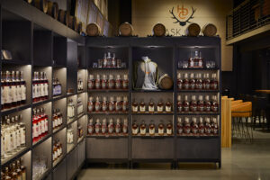 A wooden shelf holds rows of Heritage Distilling Co. liquor and other items.