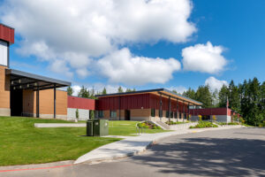 The entry of a middle school with a wood overhang at the front. The walls are colored red and gray.