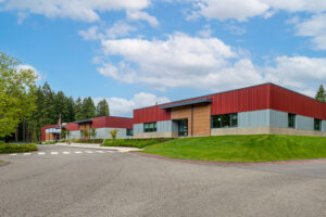 A middle school building painted half red, half gray, with intermittent wood panel accents at doorways.