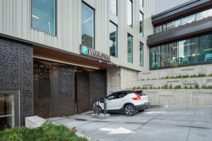 A small white car enters a parking structure at the base of a medical clinic.