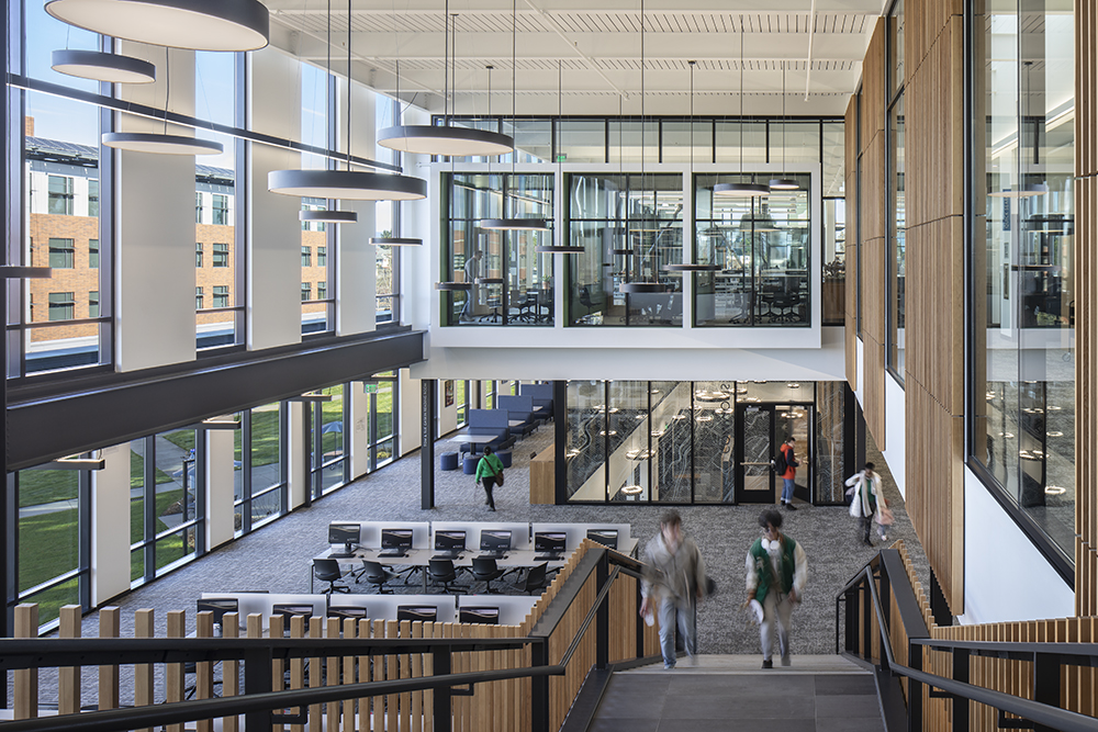 Everett-Community-College-Stair-Climb College students walk up the stairs in a large two-story atrium with floor-to-ceiling windows.