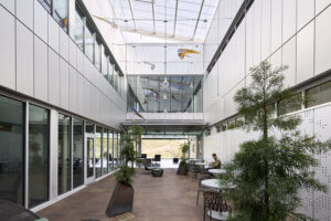 A skylight-covered courtyard with small trees and seating.