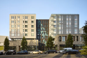 The front of a large apartment building with contrasting colored walls and many windows.