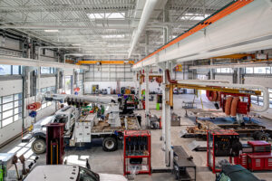 A large, white maintenance shop full of vehicles and equipment.