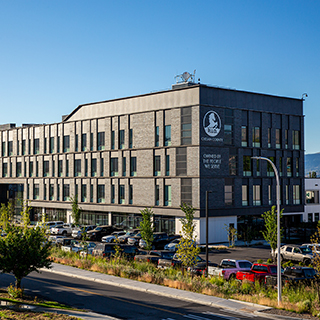 A large, rectangular brown building with four stories against a blue sky.