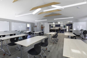 A large classroom with visible wood trusses at the ceiling and a partly unfolded operable partition wall in the back.