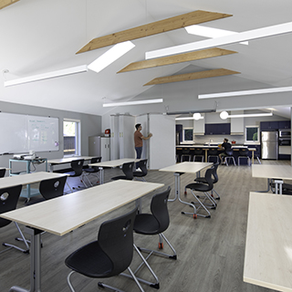 A large classroom with visible wood trusses at the ceiling and a partly unfolded operable partition wall in the back.