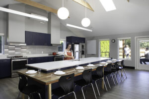 A woman stands at a large kitchen island in front of a row of blue cabinets.