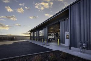 A large vehicle is visible through the open bay door of a metal garage building.