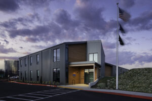 A two-story metal and wood building with a sunset in the background.